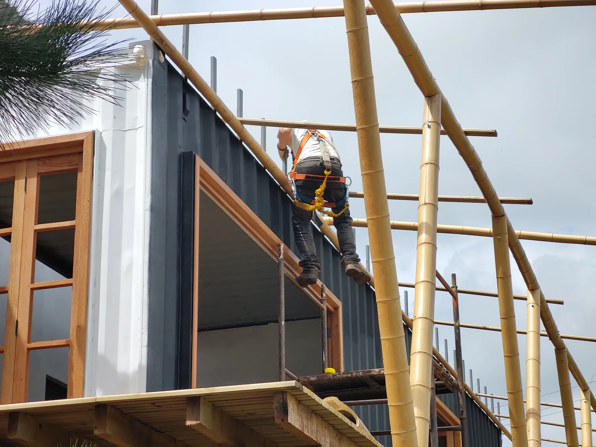 Operário com equipamento de segurança montando a estrutura de bambu da cobertura do protótipo EcoCasa.