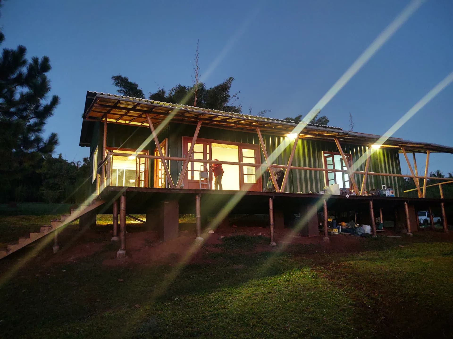 Protótipo EcoCasa finalizado: fachada verde, estrutura de bambu aparente e pilotis.
