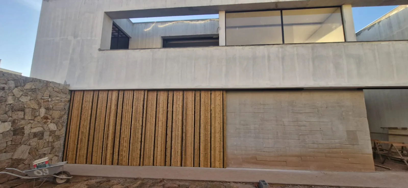 Fachada da InCasa Residence com revestimento de bambu, pedra e concreto.