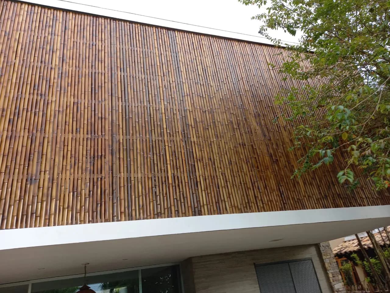 Revestimento de bambu em colmos verticais da fachada da Casa da Praia da Feiticeira, com textura envelhecida.