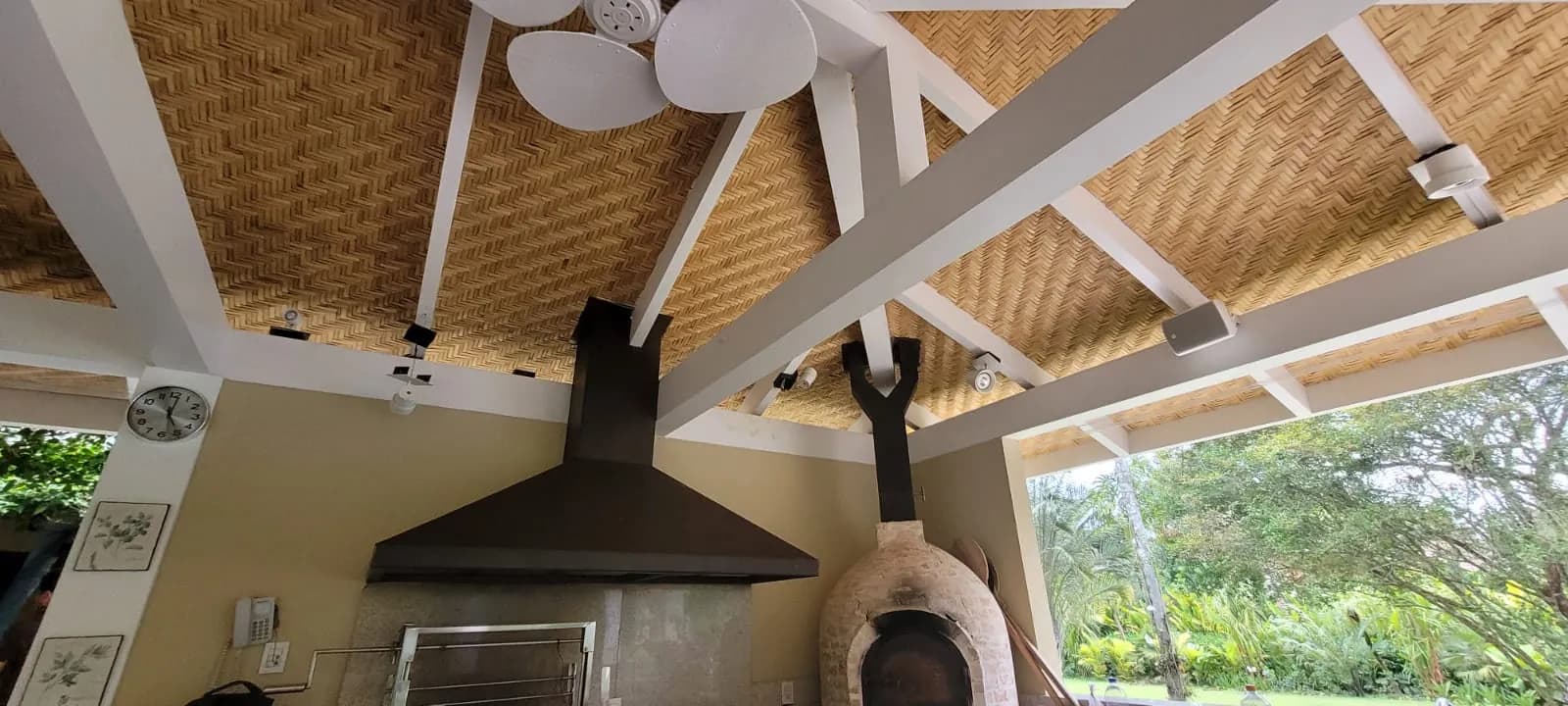 Área gourmet da Casa Iporanga sob o forro de bambu, integrada ao jardim.