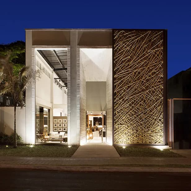 Fachada da loja Tetum ao entardecer, com a treliça de bambu iluminada e o interior visível — primeira versão (2014).