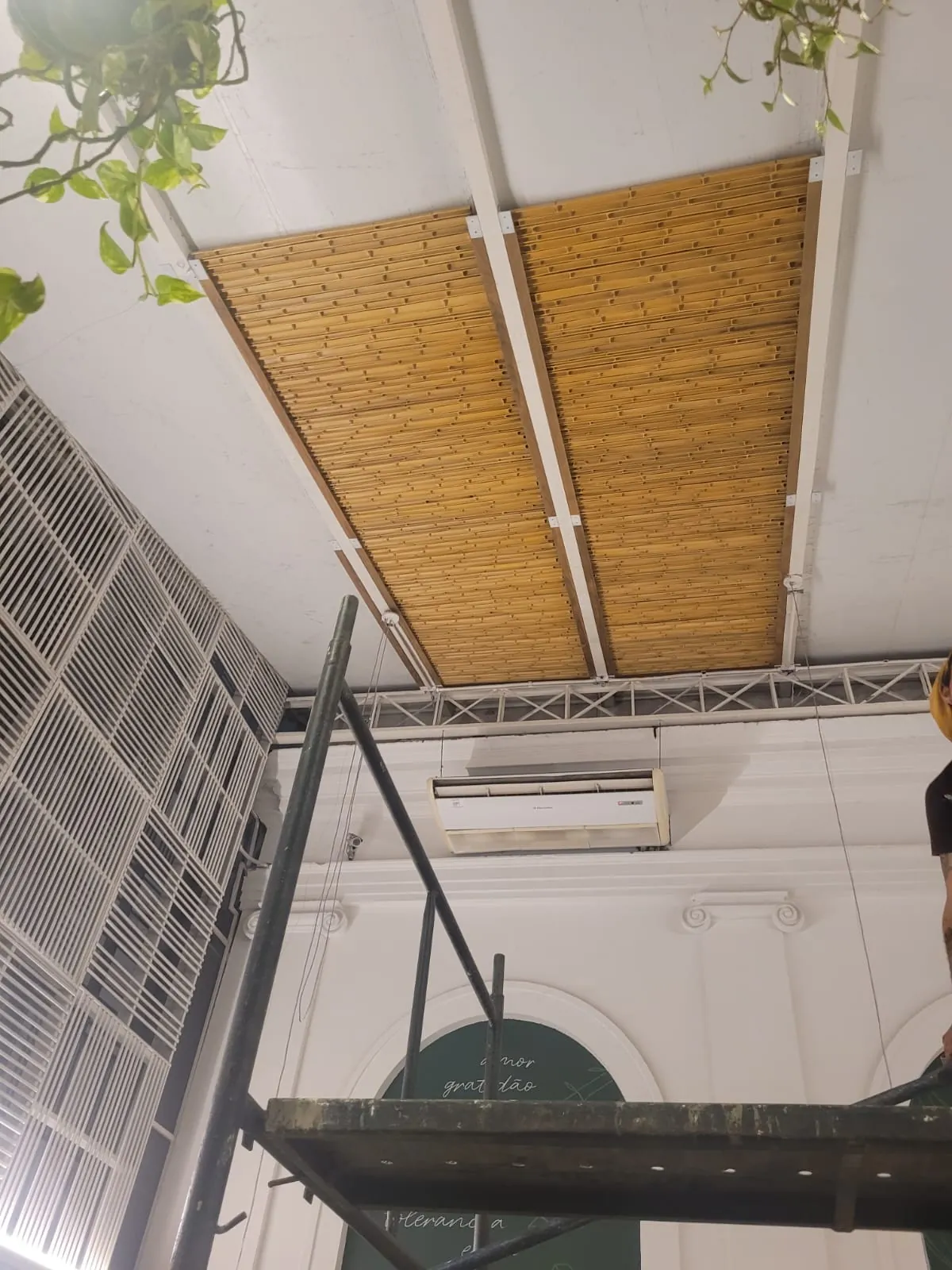 Capim Santo — área interna: forro e painéis de bambu integrados à estrutura metálica do salão.