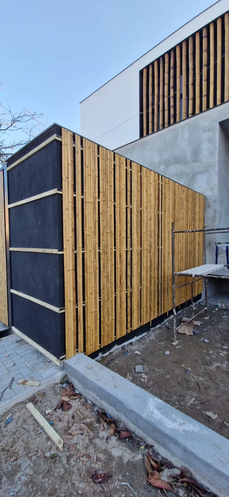 Revestimento de bambu aplicado sobre painel escuro no fechamento lateral da Casa Bombinhas.