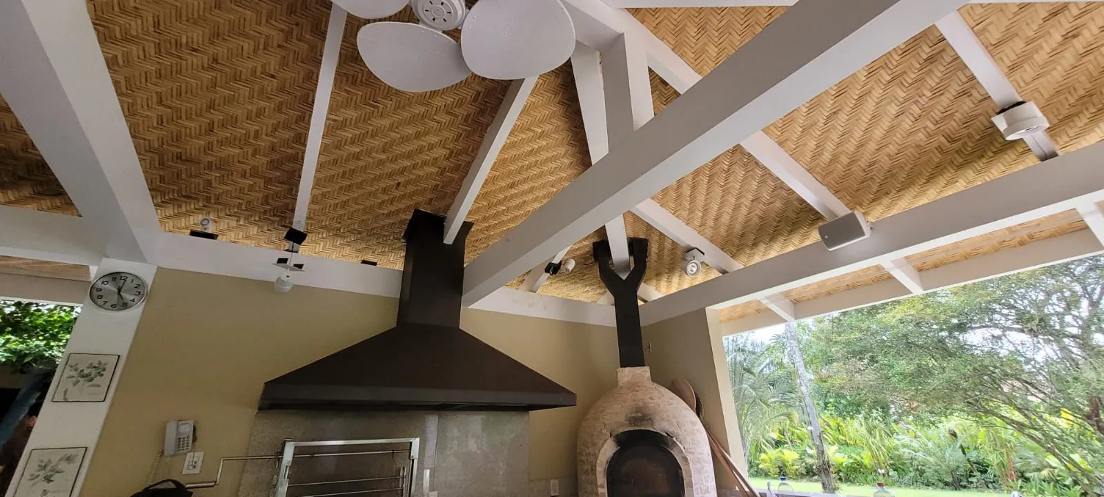 Área gourmet da Casa Iporanga sob o forro de bambu, integrada ao jardim.