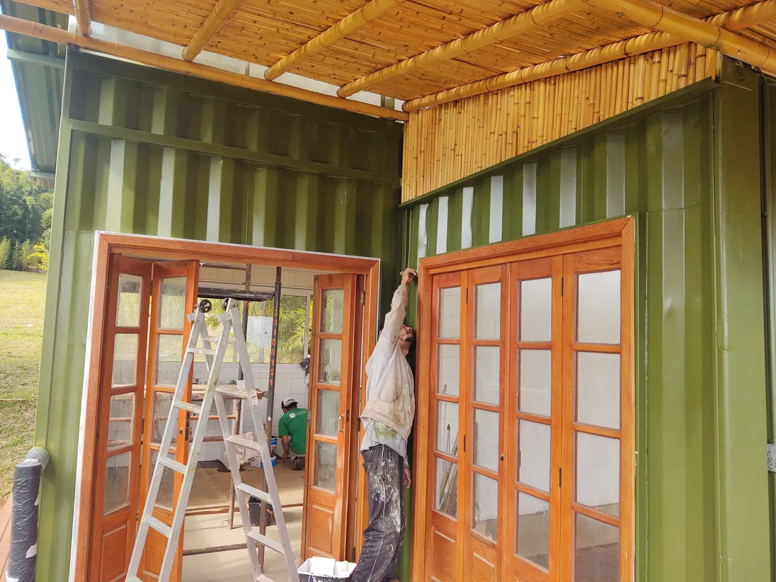 Contêiner pintado e pergolado de bambu com contraventamento em X na fachada da EcoCasa.
