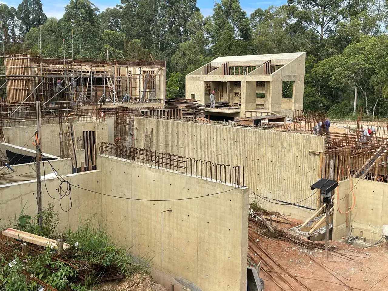 Fôrmas de concreto posicionadas em obra, com a edificação ao fundo.