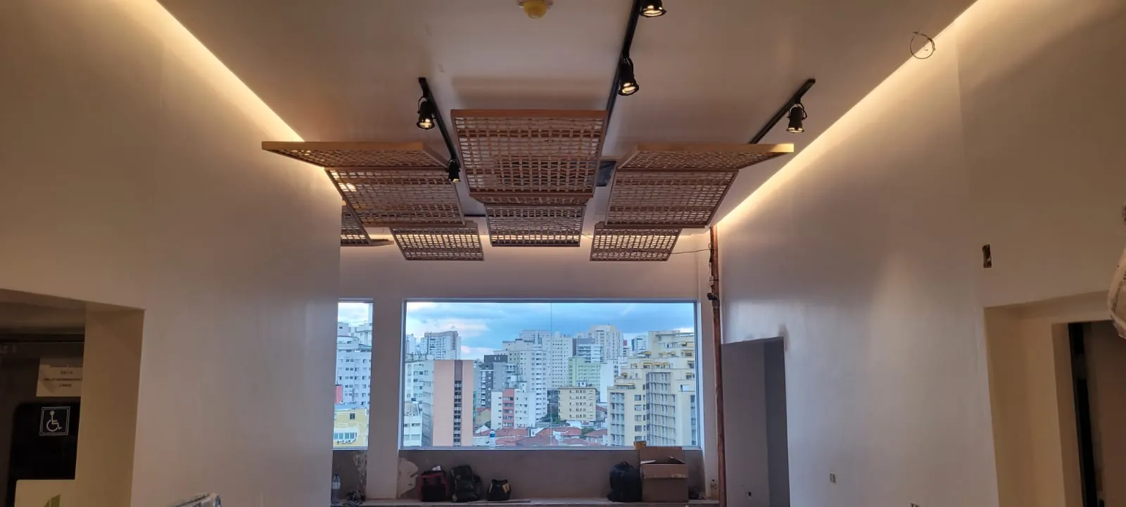 Painéis de treliça de bambu suspensos no forro do museu, com a vista da cidade ao fundo.